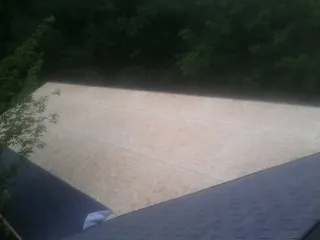 New OSB roof sheathing installed beside an existing shingle roof in Mason City