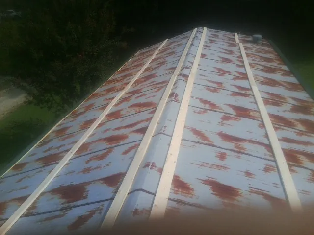 Rusted metal roof panels with new wood purlins before replacement — Storm Damage Roof Repair in Mason City by Roofing Brothers